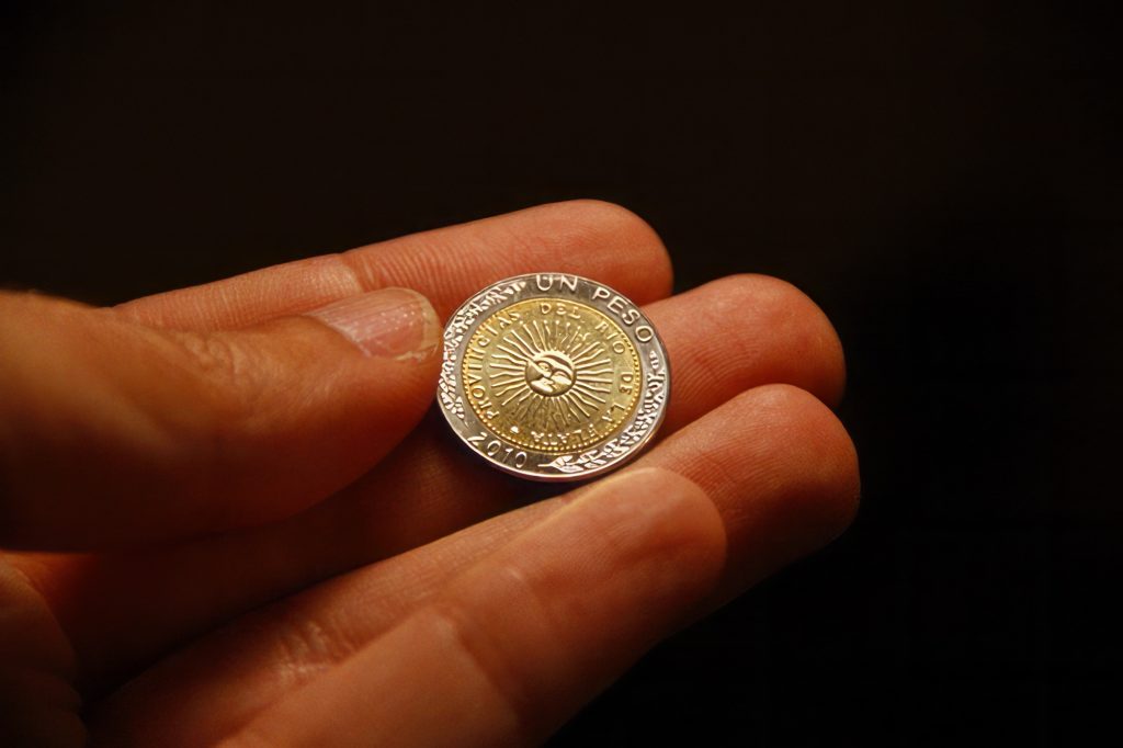 One peso coin from Argentina in hand